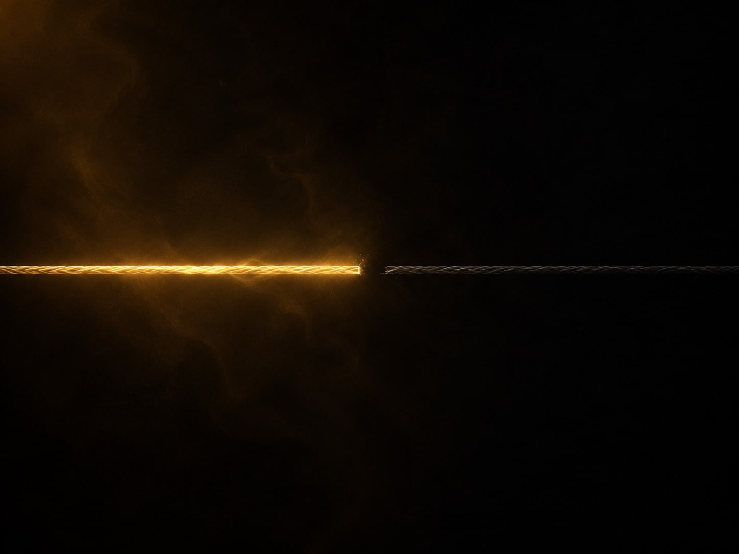 A taut gold filament glowing brightly along its first half, stopping at a clean break, the remaining length continuing unlit and dark.