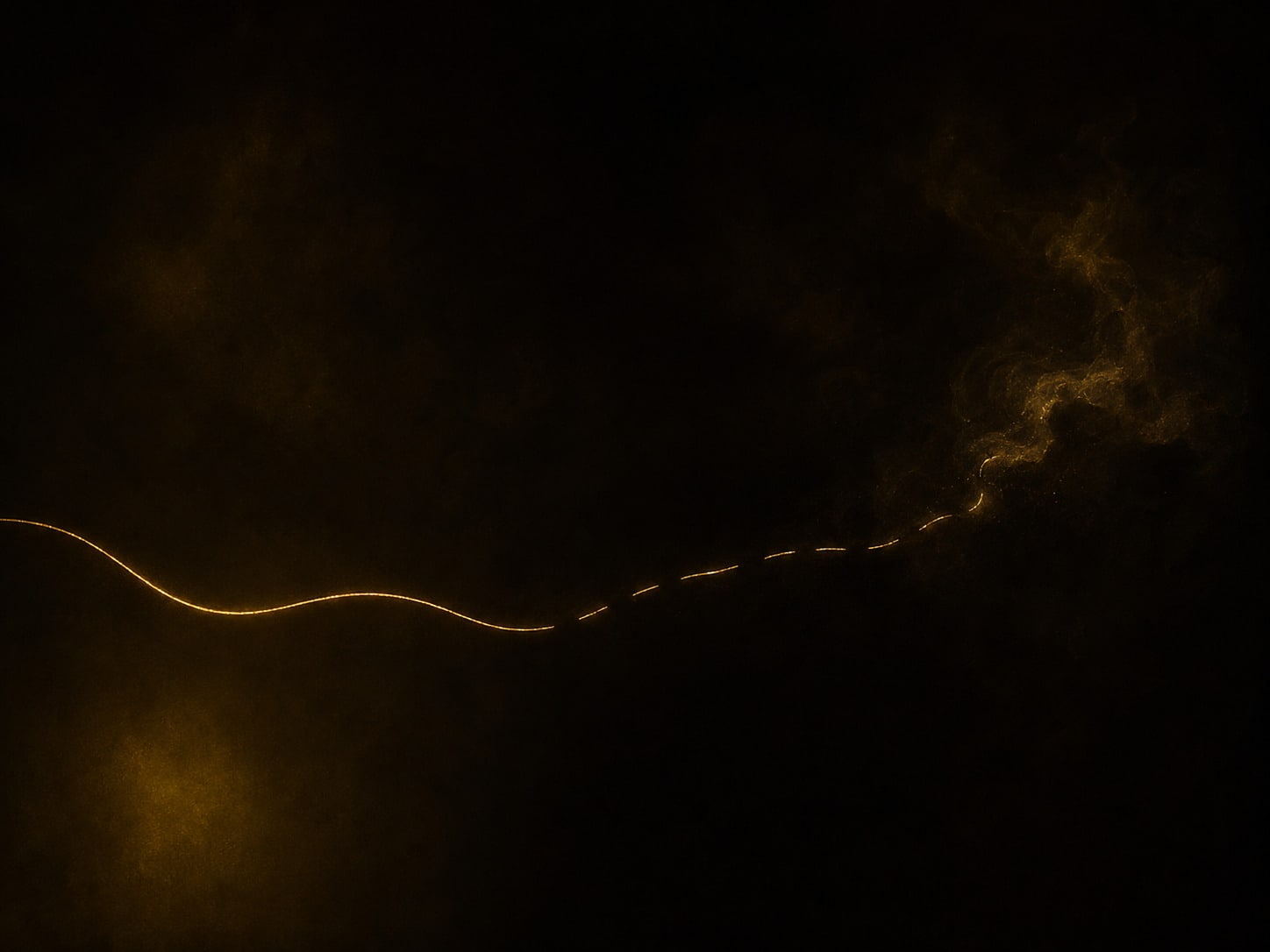 A gold thread in darkness, continuous on one side and parted into segments, with fine grain clinging at each cut end.